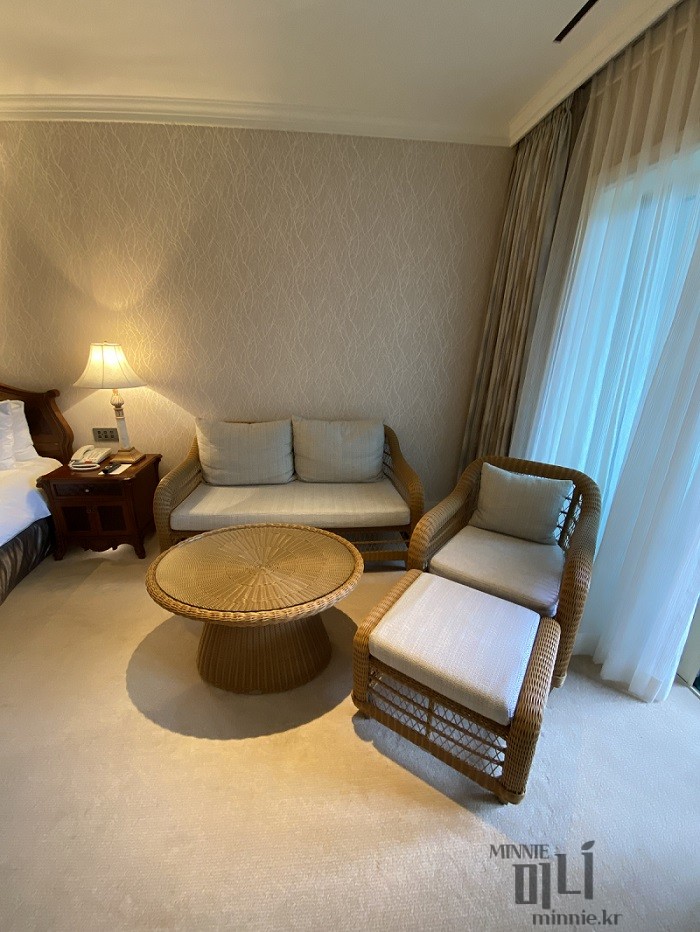 롯데호텔 제주 객실 내 비치된 아늑한 라탄 소파와 클래식한 조명 인테리어