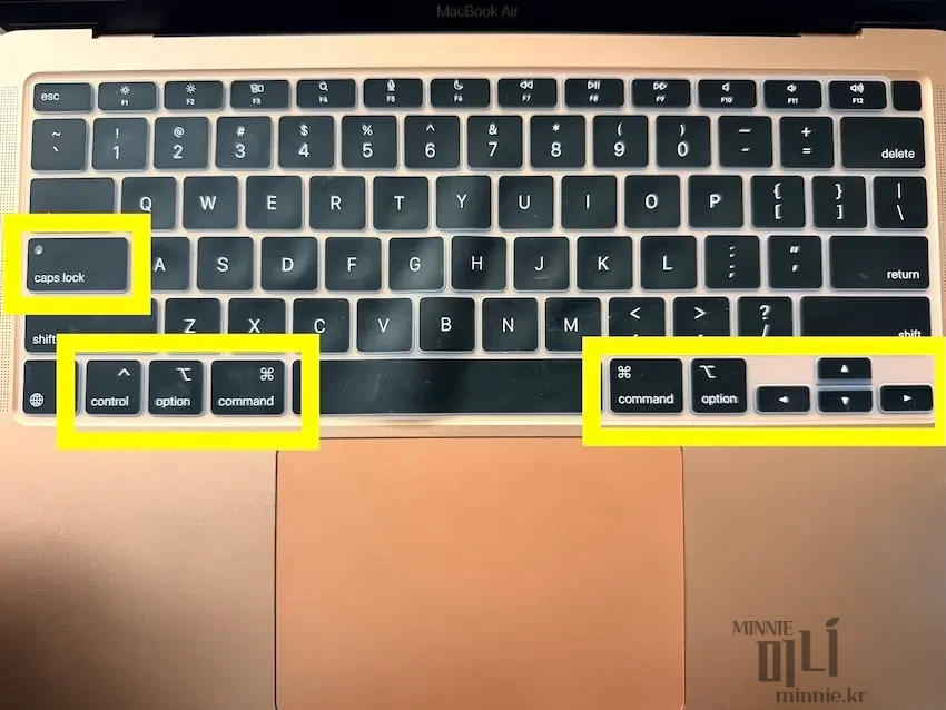 로즈 골드 컬러 맥북 에어 키보드 위에 노란색 박스로 캡스락(caps lock), 컨트롤(control), 옵션(option), 커맨드(command) 및 방향키 배열을 강조한 사진. 윈도우 유저가 알아야 할 핵심 키들이 명확히 보임.