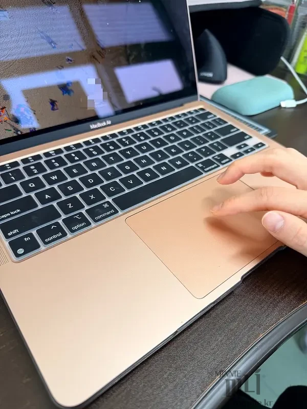 측면에서 촬영한 맥북 트랙패드 조작 모습과 세 손가락 드래그 제스처