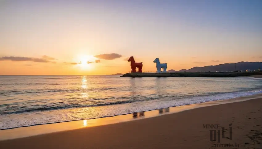 이호테우 해변의 상징인 빨간색과 하얀색 말 모양 등대 너머로 노랗게 해가 지는 아름다운 일몰 풍경