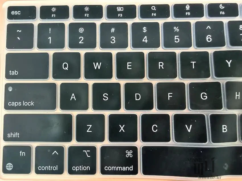 맥북 키보드의 왼쪽 Caps Lock 키를 위에서 내려다본 모습. 검은색 키캡에 'caps lock' 글자와 흰색 LED 표시등이 보입니다.